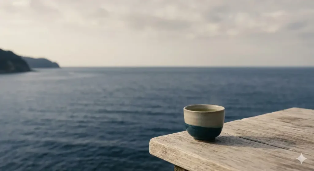穏やかな海辺の風景と木製テーブルに置かれた湯呑み。落ち着いたネイビーとベージュのトーンで「メンタルを守る」の静謐な世界観を表現。